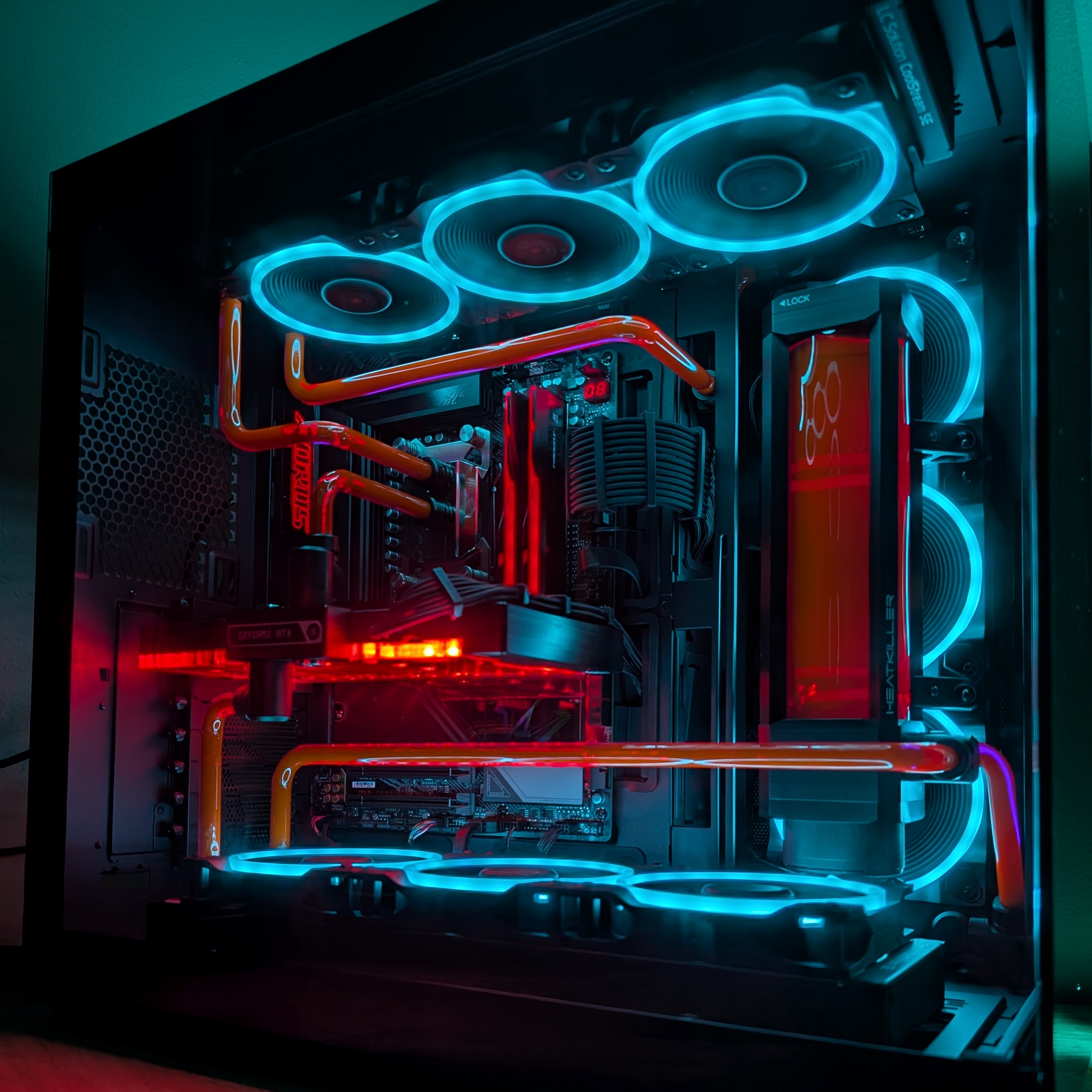 Open-air PC build with hardline watercooling loop, orange tubing, and RGB fans